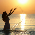 Self Worth: Woman at the beach splashing water during sunset